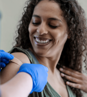 curly hair women getting band-aid on her right arm