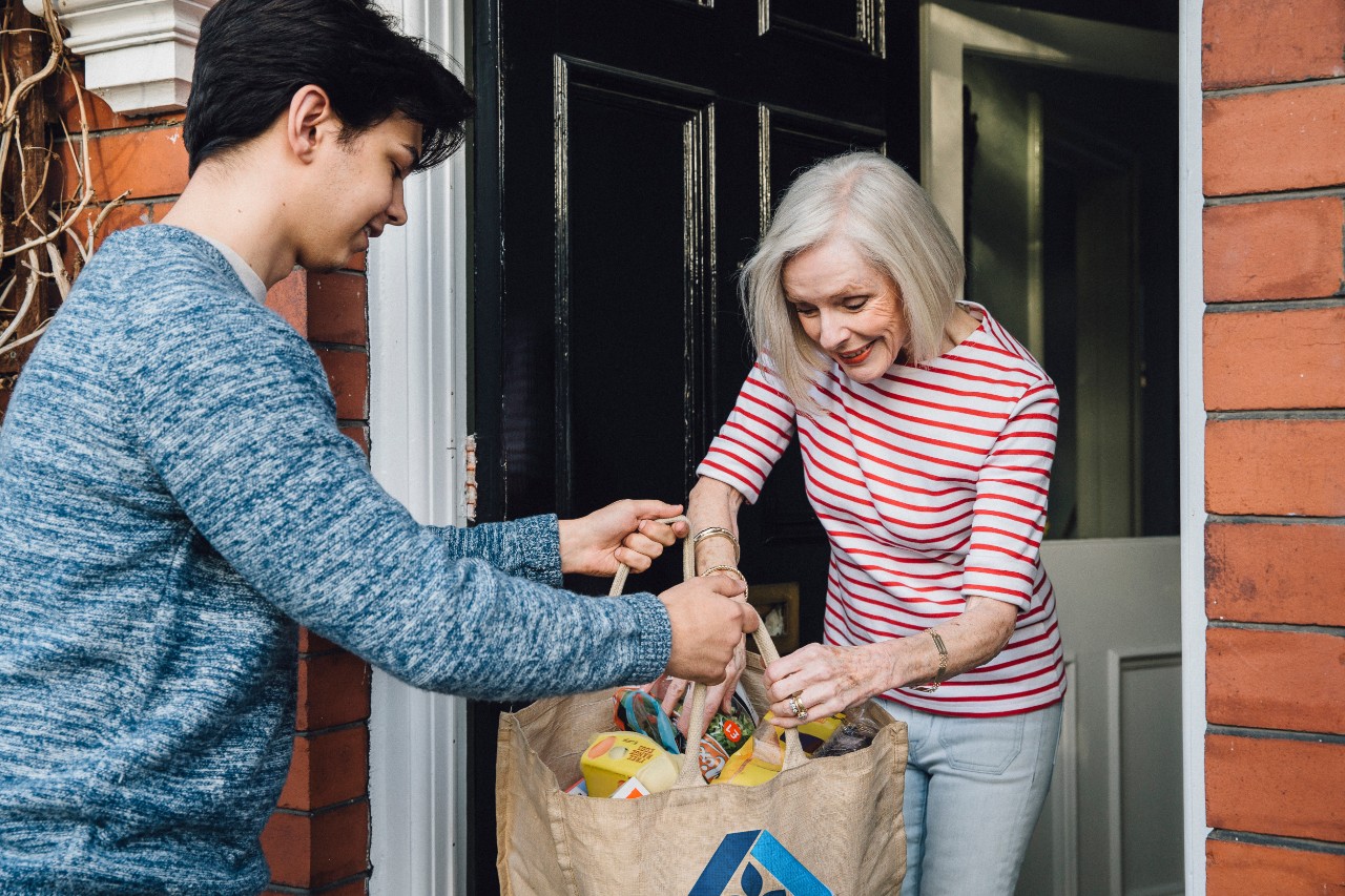 Older woman receiving a grocery delivery from a young man