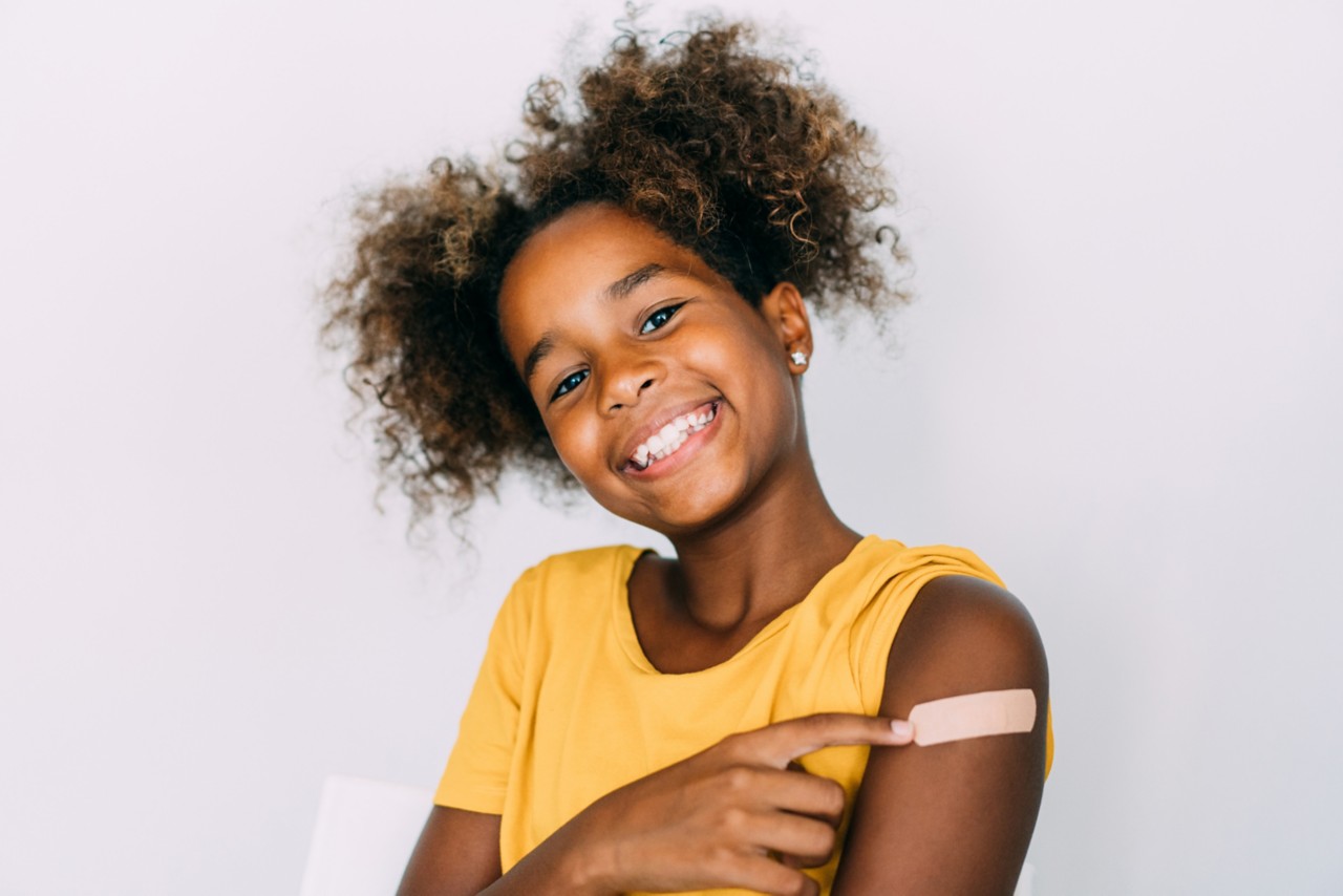 Smiling girl child pointing to bandage on left arm