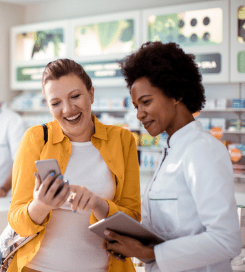 smiling woman showing mobile to pharmacist