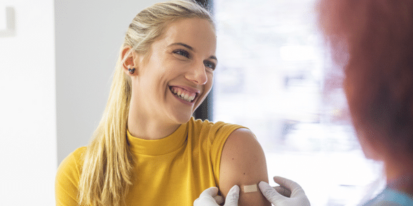 woman smiling while getting band-aid on her left hand